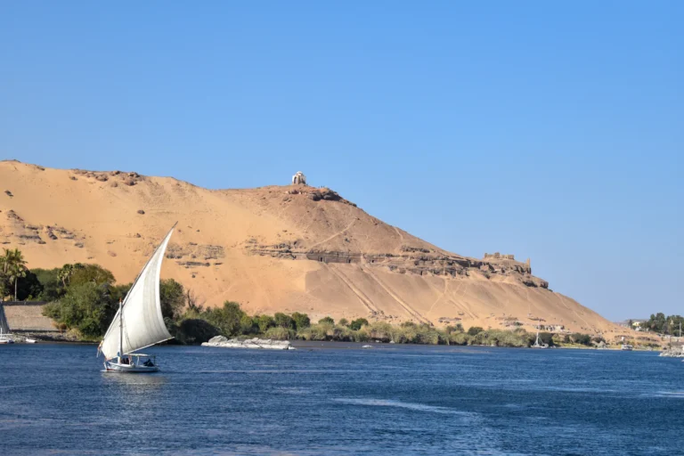 Felucca sailboat on the Nile at Aswan with desert dunes behind